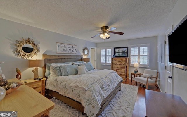 bedroom featuring hardwood / wood-style floors, a textured ceiling, and ceiling fan