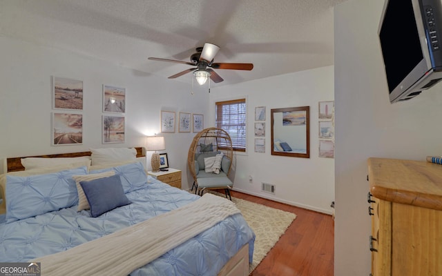 bedroom featuring ceiling fan, wood-type flooring, and a textured ceiling