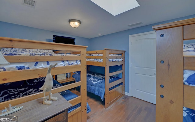 bedroom with light hardwood / wood-style floors and a skylight