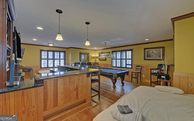 interior space with crown molding, pendant lighting, light hardwood / wood-style floors, and kitchen peninsula