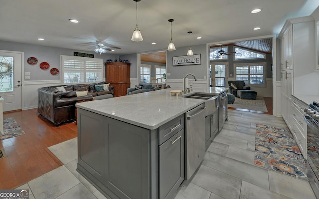 kitchen with pendant lighting, an island with sink, gray cabinetry, white cabinets, and stainless steel appliances