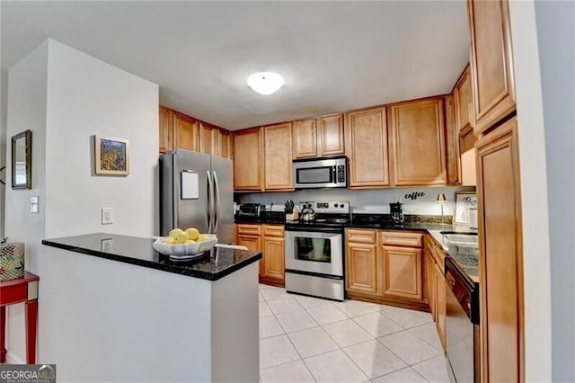 kitchen with light tile patterned floors, dark stone counters, kitchen peninsula, and appliances with stainless steel finishes