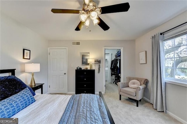 carpeted bedroom with a walk in closet, a closet, and ceiling fan