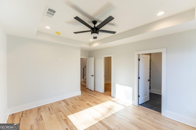 unfurnished bedroom featuring a tray ceiling and light hardwood / wood-style floors