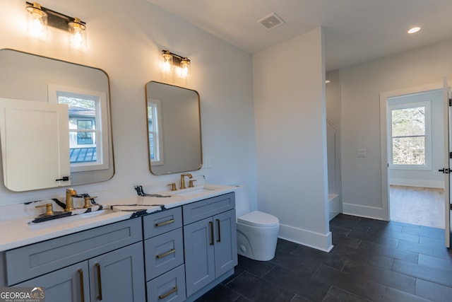 bathroom with a healthy amount of sunlight, toilet, and vanity