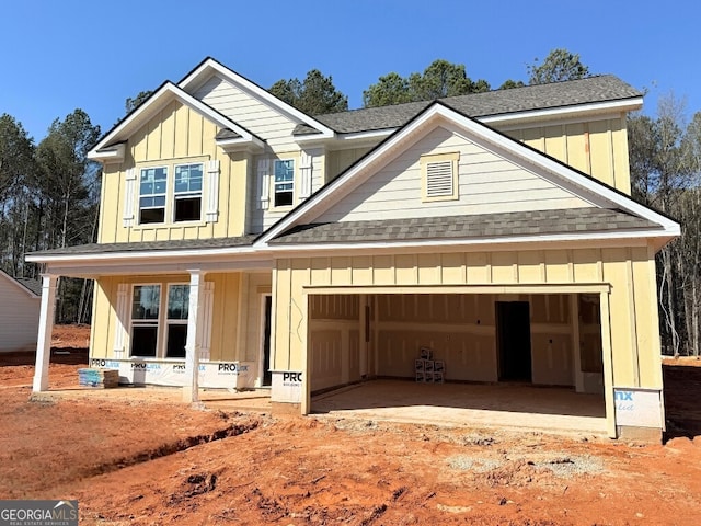 view of front of house with an attached garage, covered porch, board and batten siding, and a shingled roof