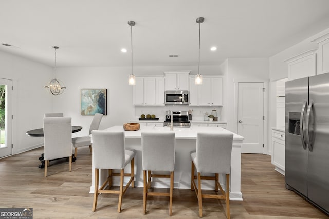 kitchen featuring light countertops, a kitchen breakfast bar, light wood-style floors, and appliances with stainless steel finishes