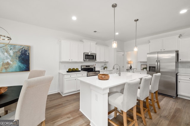 kitchen with a kitchen bar, light wood-style floors, backsplash, and stainless steel appliances