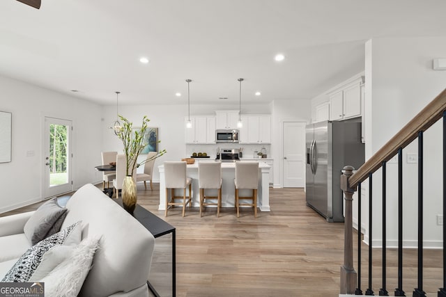 living room with recessed lighting, baseboards, light wood-style floors, and stairs