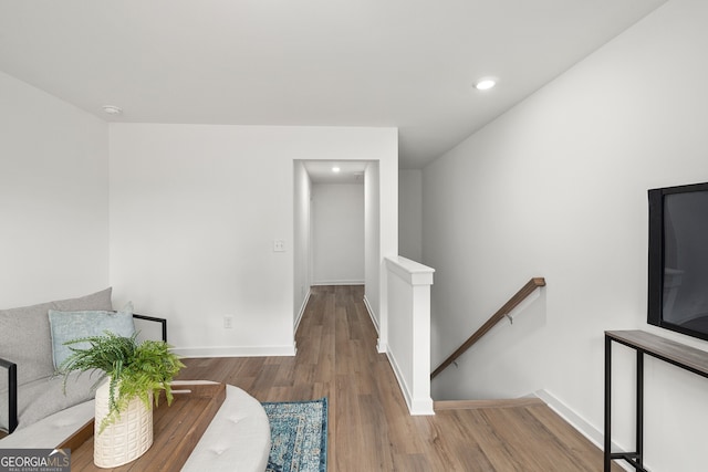 sitting room with wood finished floors, recessed lighting, an upstairs landing, and baseboards