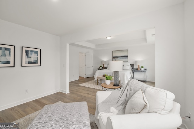 living room with a tray ceiling, baseboards, and wood finished floors