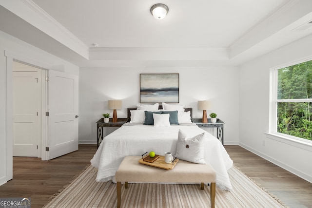 bedroom with a tray ceiling, baseboards, wood finished floors, and crown molding