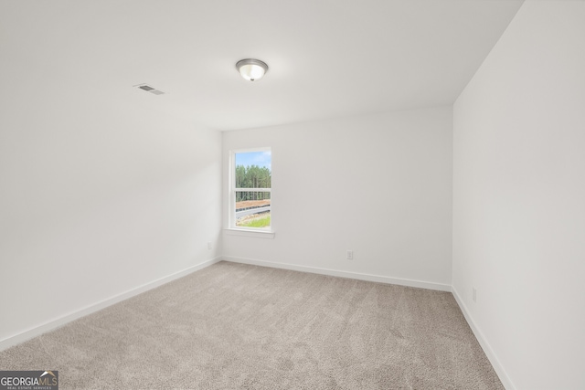 empty room with light colored carpet, visible vents, and baseboards