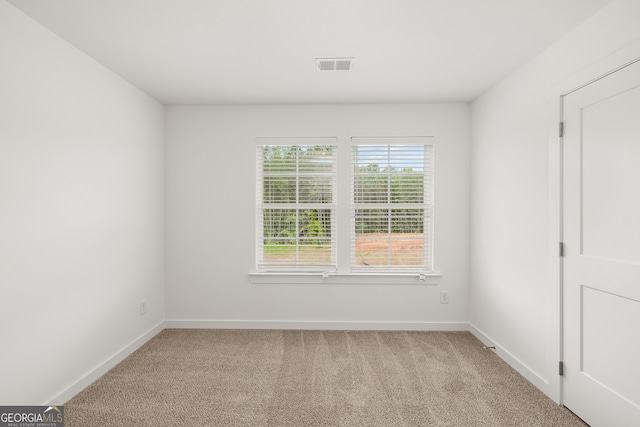 unfurnished room with light carpet, visible vents, and baseboards