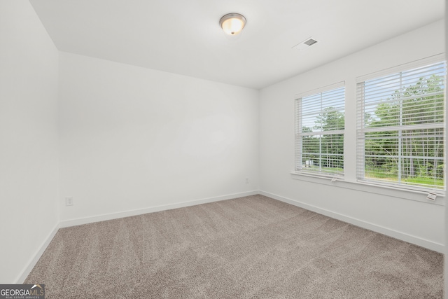 carpeted spare room with visible vents and baseboards