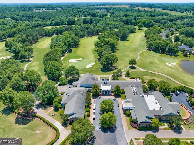 bird's eye view with a forest view and view of golf course