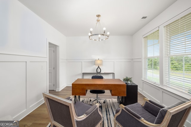 office with visible vents, a decorative wall, an inviting chandelier, and wood finished floors