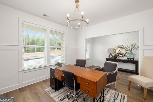 office area featuring visible vents, a healthy amount of sunlight, a decorative wall, and light wood-style floors