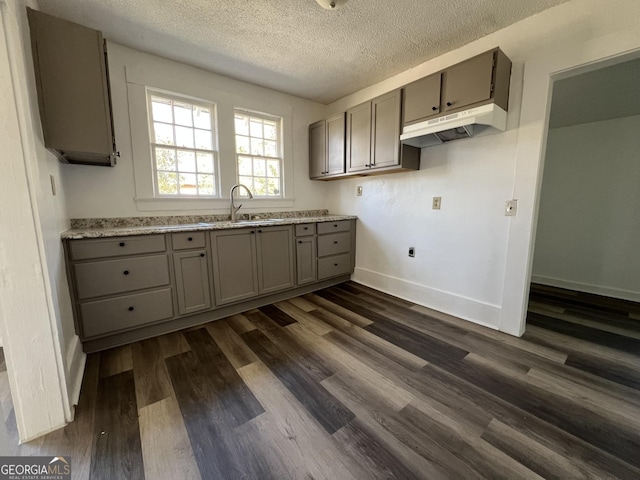 kitchen with sink, gray cabinetry, light stone counters, a textured ceiling, and dark hardwood / wood-style flooring