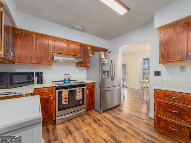 kitchen featuring stainless steel appliances, light hardwood / wood-style floors, and a textured ceiling