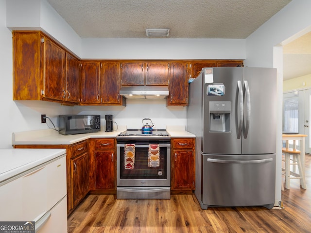 kitchen featuring stainless steel appliances, hardwood / wood-style flooring, and a textured ceiling