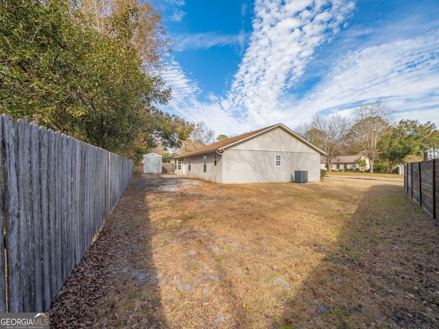 view of yard with central AC and a storage shed