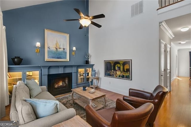 living room featuring hardwood / wood-style flooring, a towering ceiling, and ceiling fan