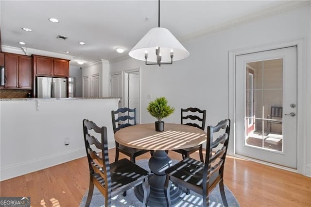 dining space with crown molding and light hardwood / wood-style floors