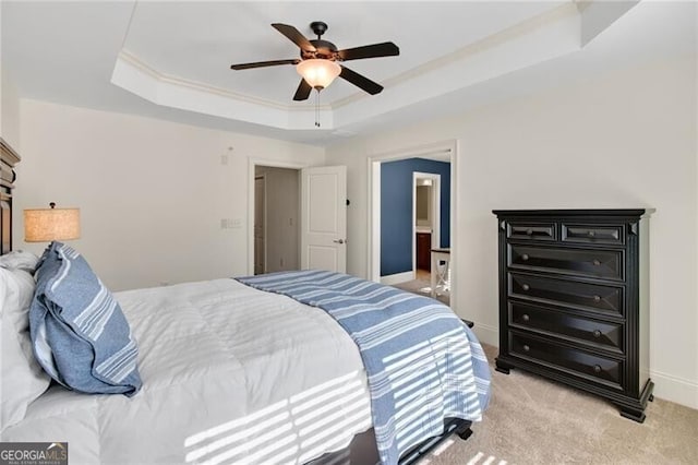 bedroom featuring ornamental molding, light colored carpet, ceiling fan, a raised ceiling, and ensuite bath