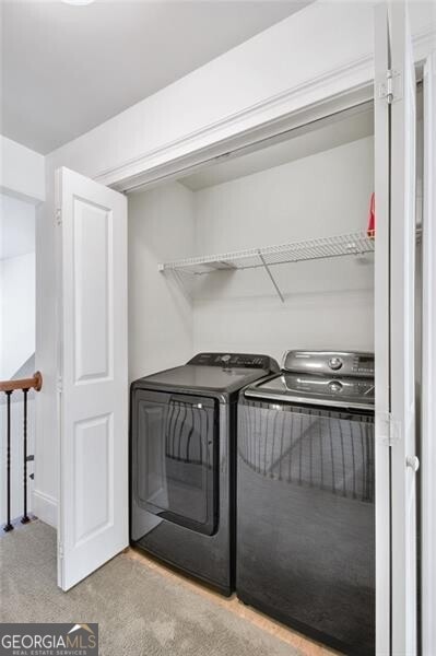 laundry area with washing machine and clothes dryer and light colored carpet