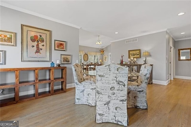 dining room with crown molding, ceiling fan, and light wood-type flooring