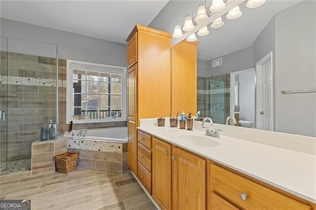 full bathroom with shower with separate bathtub, vanity, an inviting chandelier, and toilet