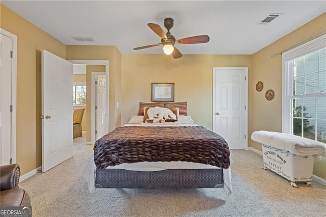 bedroom featuring ceiling fan, light carpet, and multiple windows