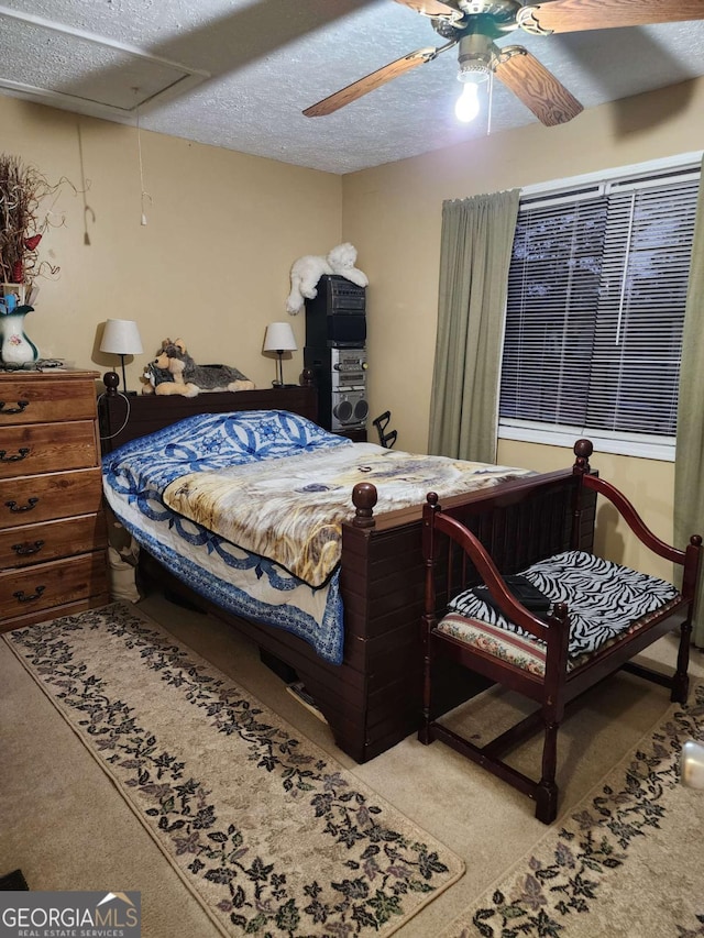 carpeted bedroom featuring ceiling fan and a textured ceiling