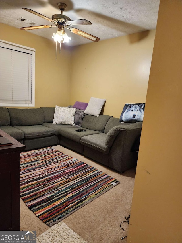 carpeted living room with ceiling fan and a textured ceiling