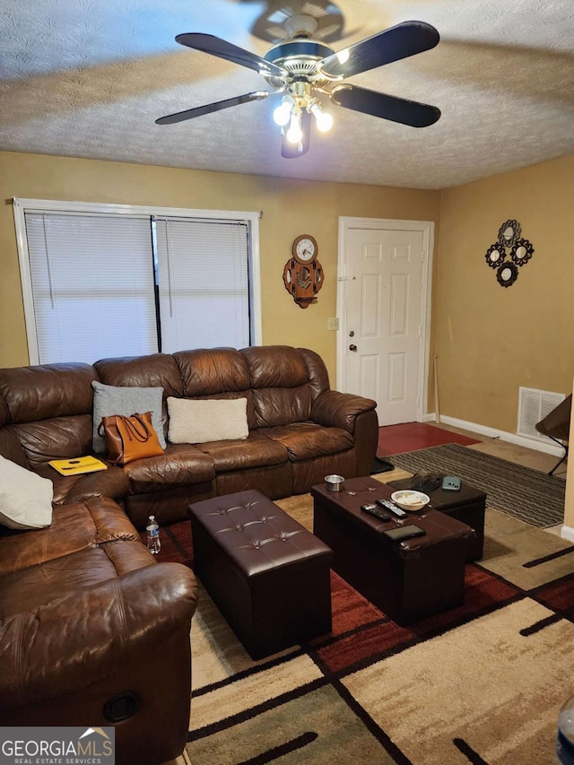 living room featuring ceiling fan and a textured ceiling