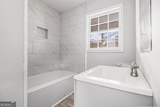 bathroom featuring hardwood / wood-style flooring, tiled shower / bath, and vanity