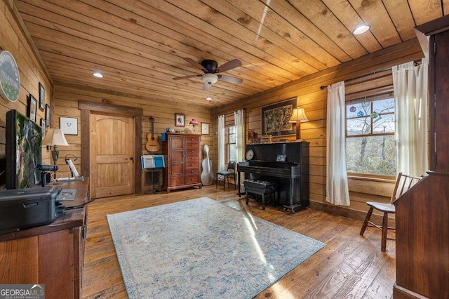 living area featuring hardwood / wood-style floors, wooden walls, wooden ceiling, and ceiling fan