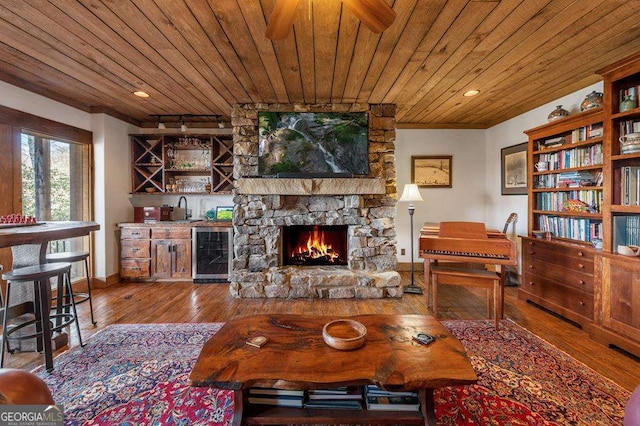 living room featuring hardwood / wood-style floors, a fireplace, wine cooler, wood ceiling, and wet bar