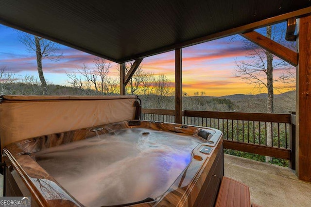 deck at dusk featuring a hot tub