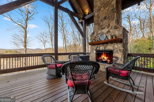 deck with a mountain view and an outdoor stone fireplace