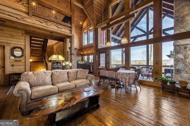 living room with dark wood-type flooring, wood walls, and a towering ceiling