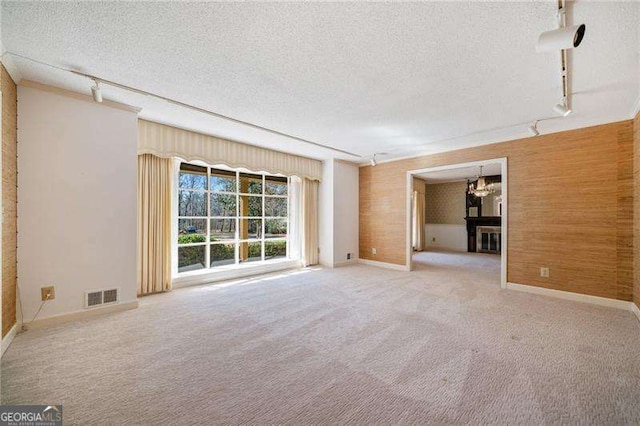 carpeted spare room with rail lighting, a chandelier, and a textured ceiling