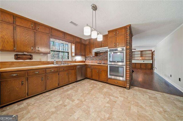 kitchen featuring stainless steel appliances, sink, a textured ceiling, and decorative light fixtures