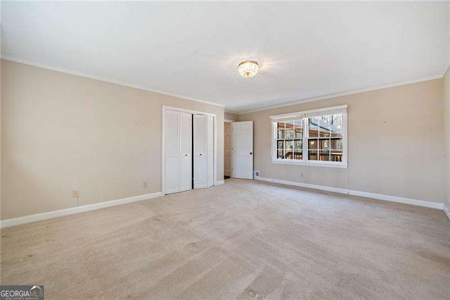 unfurnished bedroom with crown molding, a closet, and light carpet