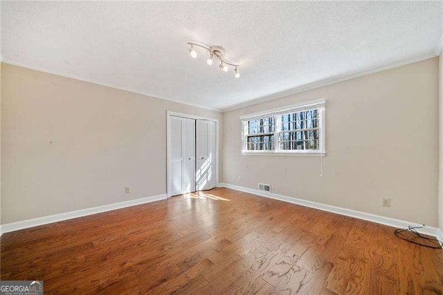 unfurnished room with ornamental molding, wood-type flooring, and a textured ceiling