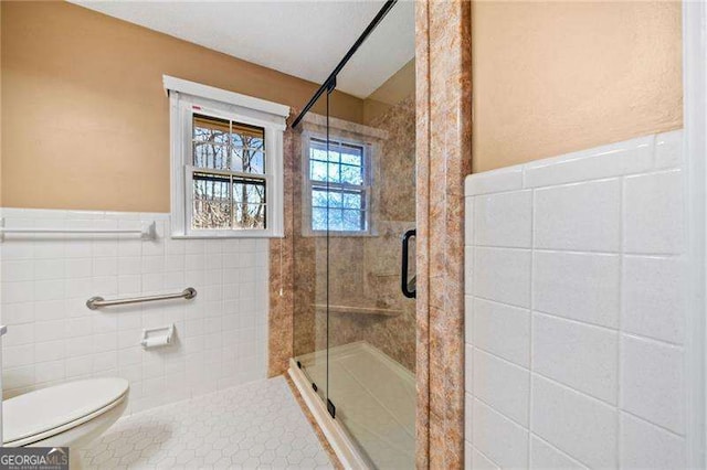 bathroom featuring tile walls, an enclosed shower, and toilet