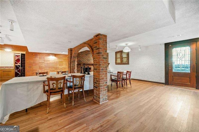 interior space with decorative columns, a textured ceiling, and light hardwood / wood-style flooring