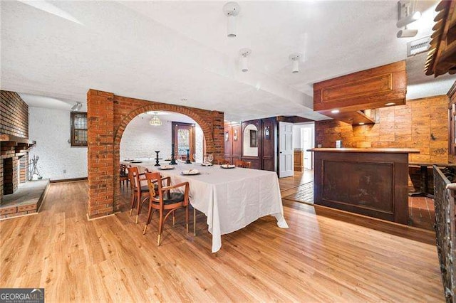 dining room featuring brick wall, a fireplace, and light hardwood / wood-style floors