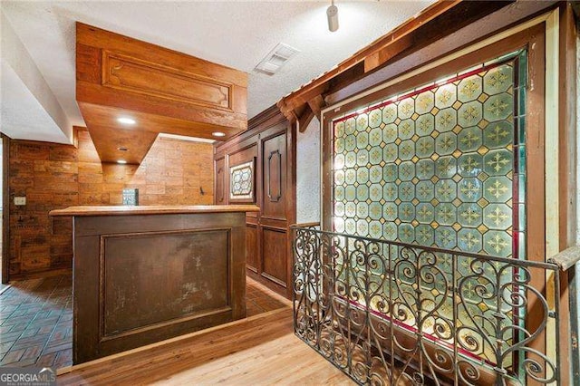 wine cellar with wood-type flooring, wooden walls, and bar area